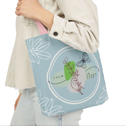 Person holding a tote bag with nature-themed design and text.